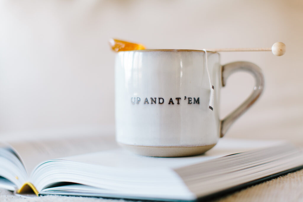 image of a mug sitting on an open book with the words up and at 'em printed on the mug