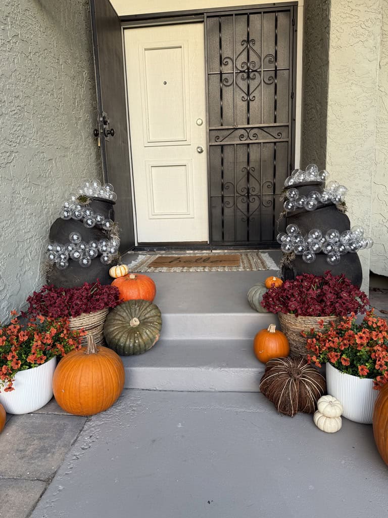 DIY bubbling cauldrons on a porch with pumpkins and mums