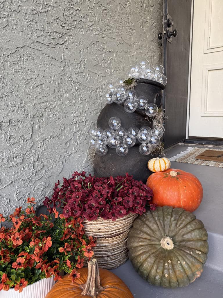 a stack of fake bubbling cauldrons surrounded by pumpkins and mums