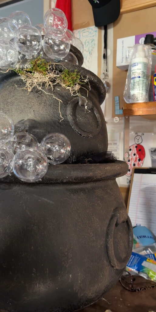add fake moss to a stack of fake bubbling cauldrons