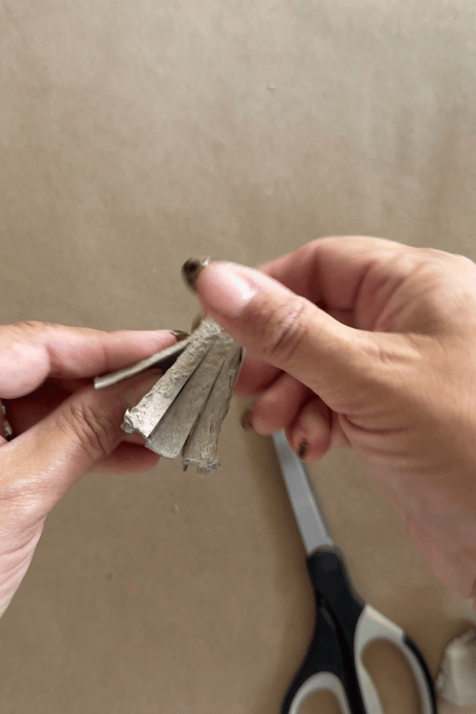 Cut small slits in the pointy piece of an egg carton to look like a broom