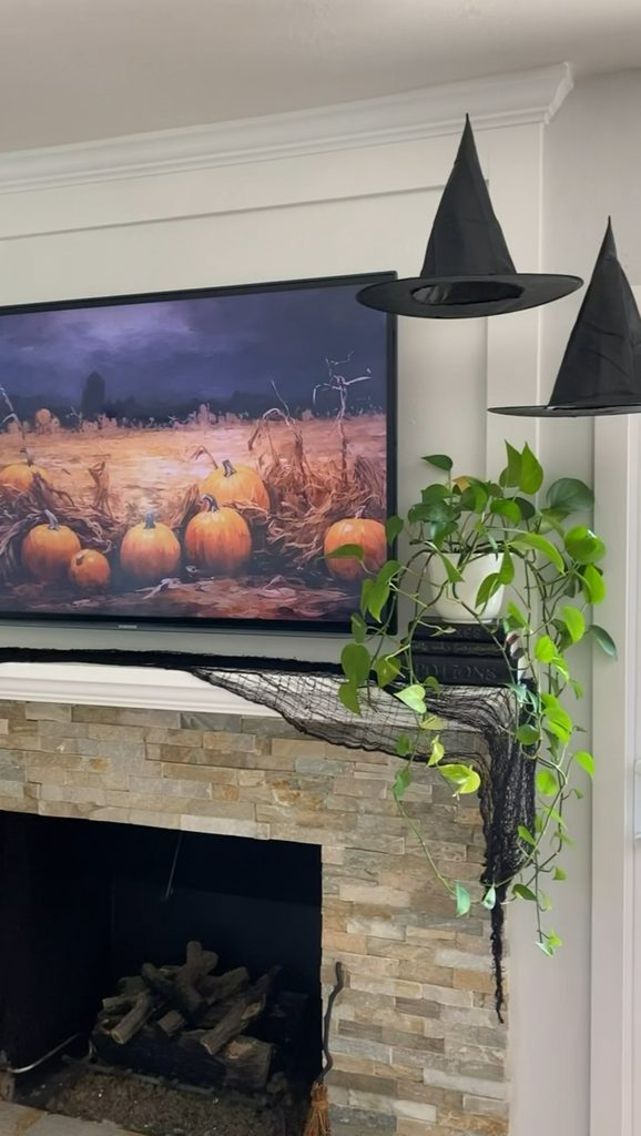 witch hats hanging from ceiling and spooky fabric draped over mantel